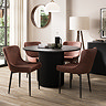 image of four faux leather dining chairs with black legs tucked under black round dining table