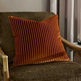 55x55cm brick orange cushion with vertical stripe detail, sat on dark khaki armchair