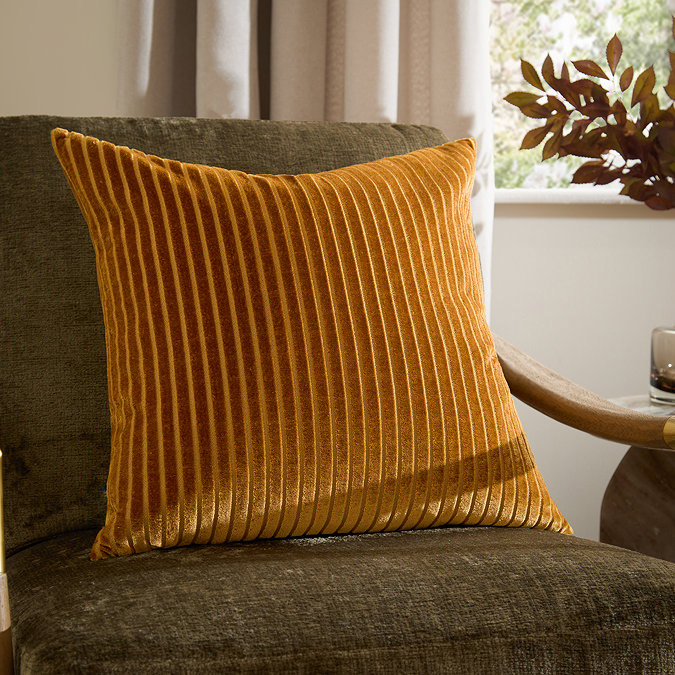 55x55cm gold cushion with vertical stripe detailing, sat on dark khaki chair