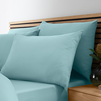 image of four pillows in duck egg blue pillowcases on a bed with matching duvet cover and fitted sheet