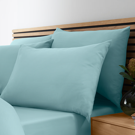 image of four pillows in duck egg blue pillowcases on a bed with matching duvet cover and fitted sheet