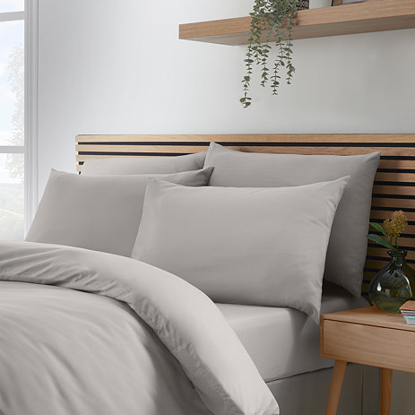 4 pillows on a bed covered in so soft grey pillowcases