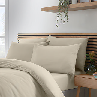 set of 4 natural coloured pillowcases on a bed with matching duvet and fitted sheet