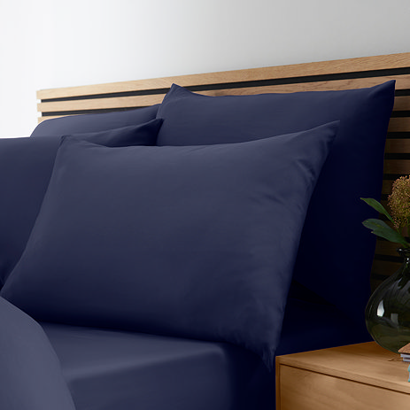 set of 4 navy pillowcases on bed with matching fitted sheet