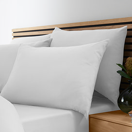 image of four pillows in white pillowcases on bed with matching duvet and fitted sheet