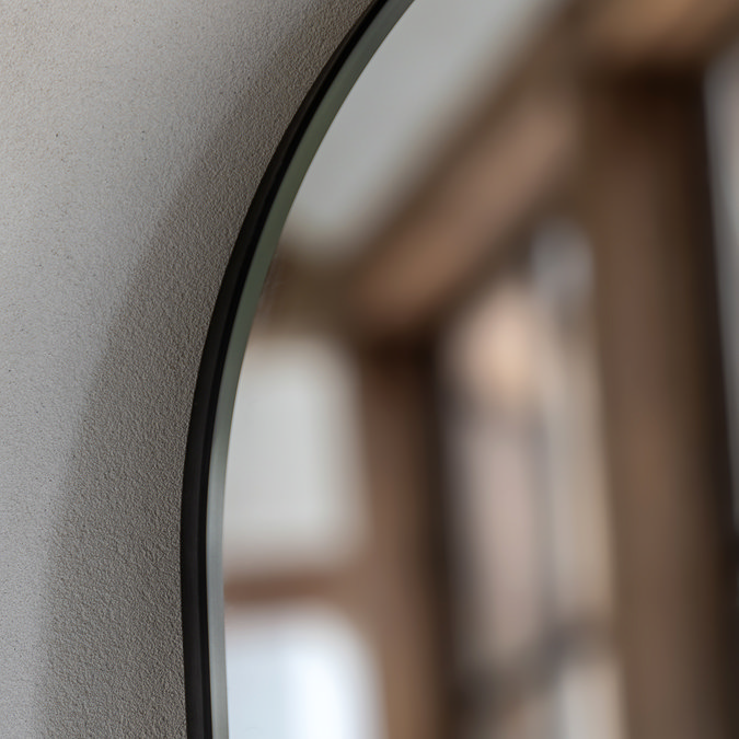 close up image on rounded black edge of floor mirror, focus on smooth glass