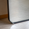 close up image of rounded bottom edge of black floor length mirror