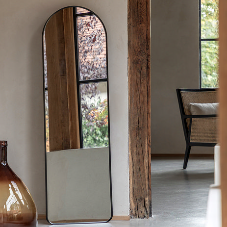 image of black full length freestanding mirror with rounded top against a cream wall