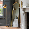 image of full length gold floor mirror leaning against a cream wall with gold floor lamp standing next to it