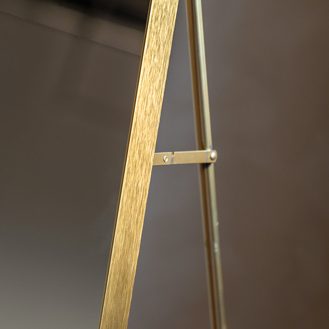 close up image of where slim supportive stand attaches to gold floor mirror