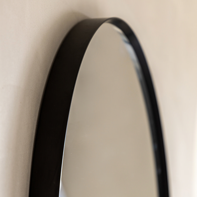 close up on smooth black edges of pebble shaped wall mirror