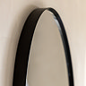 close up on smooth black edges of pebble shaped wall mirror