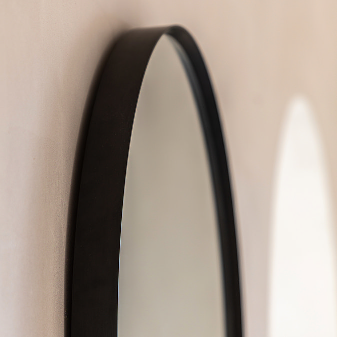 close up image of rounded top of smooth black top of black wall mirror