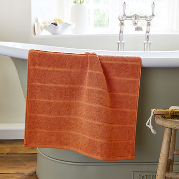 image of amber bath mat slightly rolled up at the end, on light grey background