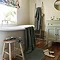 wide shot of bathroom with ash grey towels draped over the bath, on a stool, hung up on a wall, with coordinating bath mat on the floor