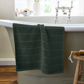 image of ash grey bath mat over the side of a bath