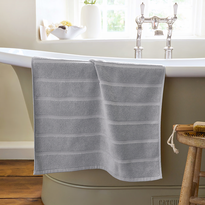 image of light grey bath mat hanging over side of bath