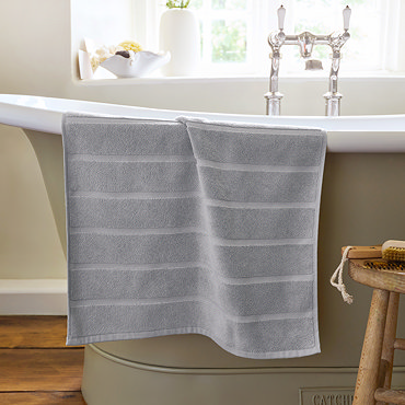 image of light grey bath mat slightly rolled up at end, on light grey background