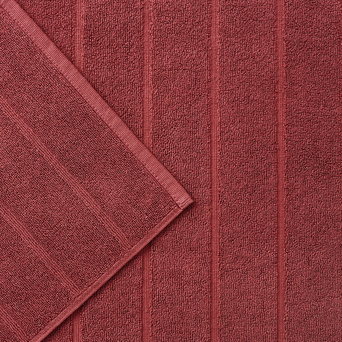 close up on wide ribbed texture of light red bath mat
