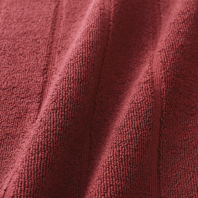 close up on colour and texture of light red bath mat