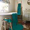 wide image of teal bath mats and towels in a bathroom