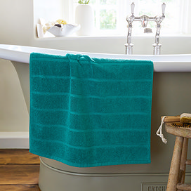 image of teal blue bath mat over the side of a bath