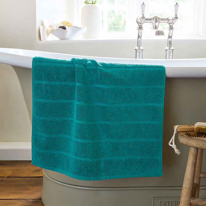image of teal blue bath mat over the side of a bath
