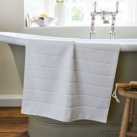 image of white bath mat draped over the side of a bath