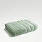 image of jade green towel folded up on light grey background