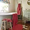 wide shot of bathroom with rouge towels draped over the bath, on a stool, hung up on a wall, with coordinating bath mat on the floor
