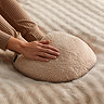 close up on hands feeling the cosy boucle texture of the heated foot warmer, in a natural colour