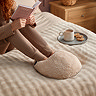 image of a woman with knees up reading a book in bed, with feet in boucle heated foot warmer