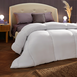 thick uncovered duvet atop a bed with purple sheet and pillows