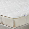 close up on corner of a bed with elastic strap securing a mattress topper in place