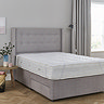 wide image of mattress protector atop a mattress on a bed with purple headboard