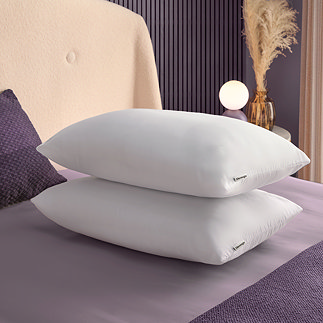 two plush white pillows stacked on top of each other on top of a purple bed sheet