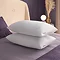 two plush white pillows stacked on top of each other on top of a purple bed sheet