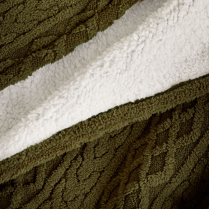 close up on cable knit material of green blanket and soft cream sherpa reverse