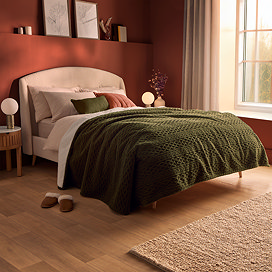 giant green cable knit blanket on the end of a bed