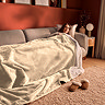 woman lying down on a sofa, covered in giant cosy natural coloured blanket