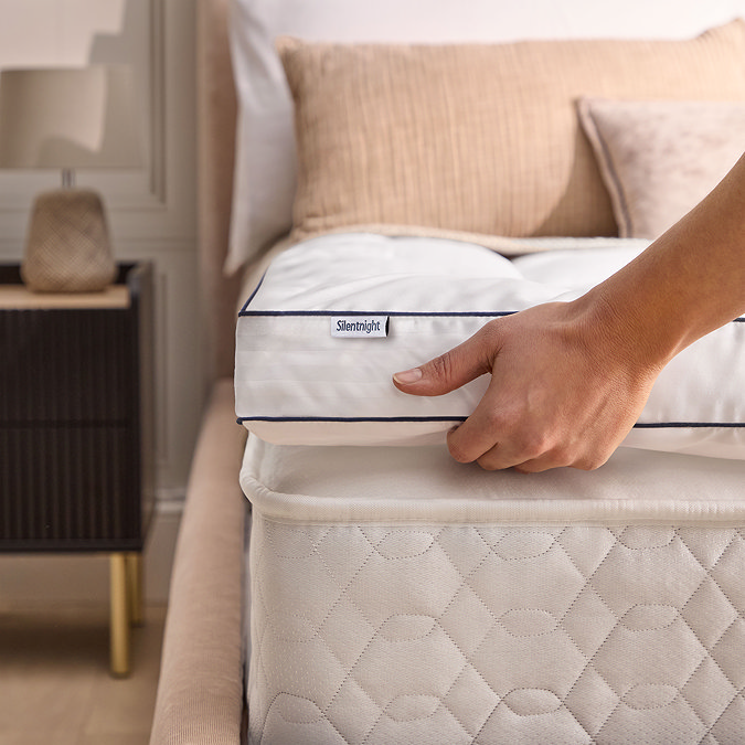 close up of a person lifting the mattress topper slightly with their hand