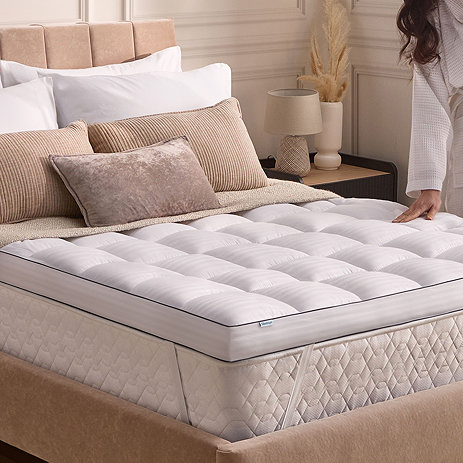 10cm deep white mattress topper on top of a mattress with person just out of frame brushing the top