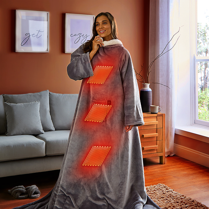 image of woman stood up in front of sofa wearing long grey blanket with sleeves, indicating length of the blanket