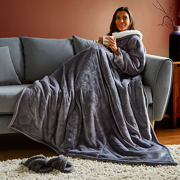 closer image of woman wearing large grey blanket, with graphic of heatwaves across body to indicated heated features