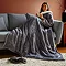 image of woman on grey sofa, covered in wearable giant grey blanket
