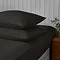 two pillows covered in black pillowcases stacked on top of one another on matching black fitted sheet