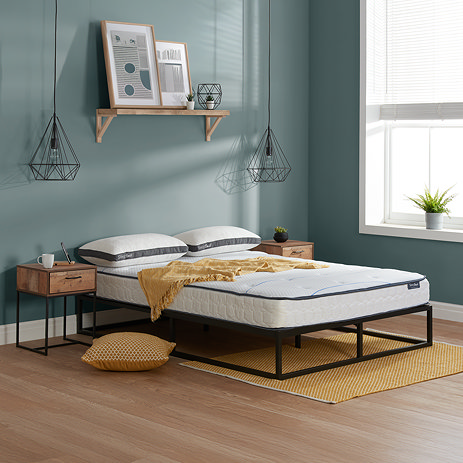 image of double mattress on a bed with black metal frame, against a light teal wall.
