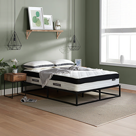 side on image of double mattress on black metal frame against light green wall