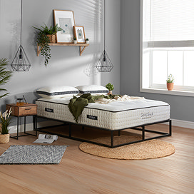 slightly side on image of deep mattress on black metal frame, pushed up against light grey wall