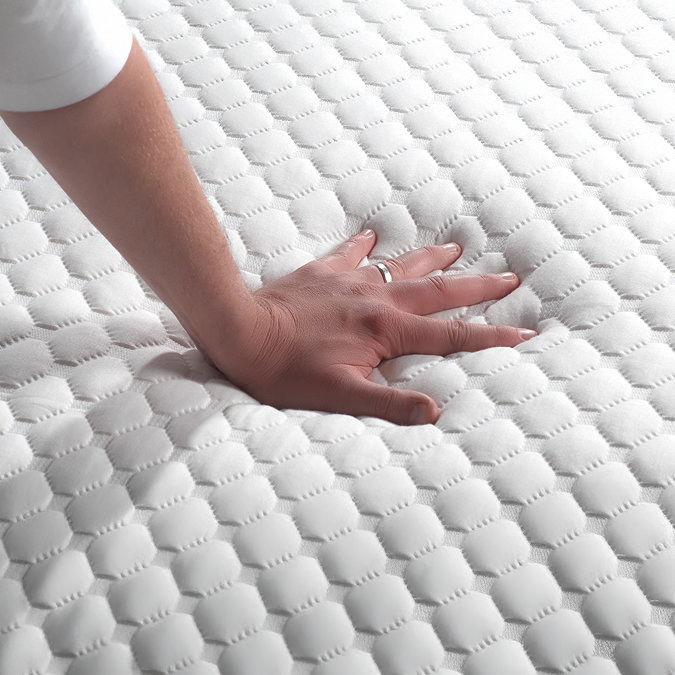 close up on hand touching top of mattress to feel texture and firmness